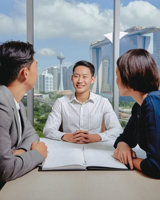 A lawyer meeting two clients across a desk with a city skyline behind